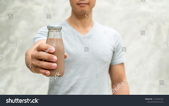 stock-photo-men-holding-a-bottle-of-chocolate-milk-on-gray-background-1151045720